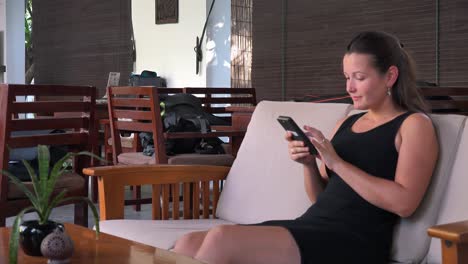 plano medio de una joven viajera sentada en la recepción de un hotel revisando su teléfono