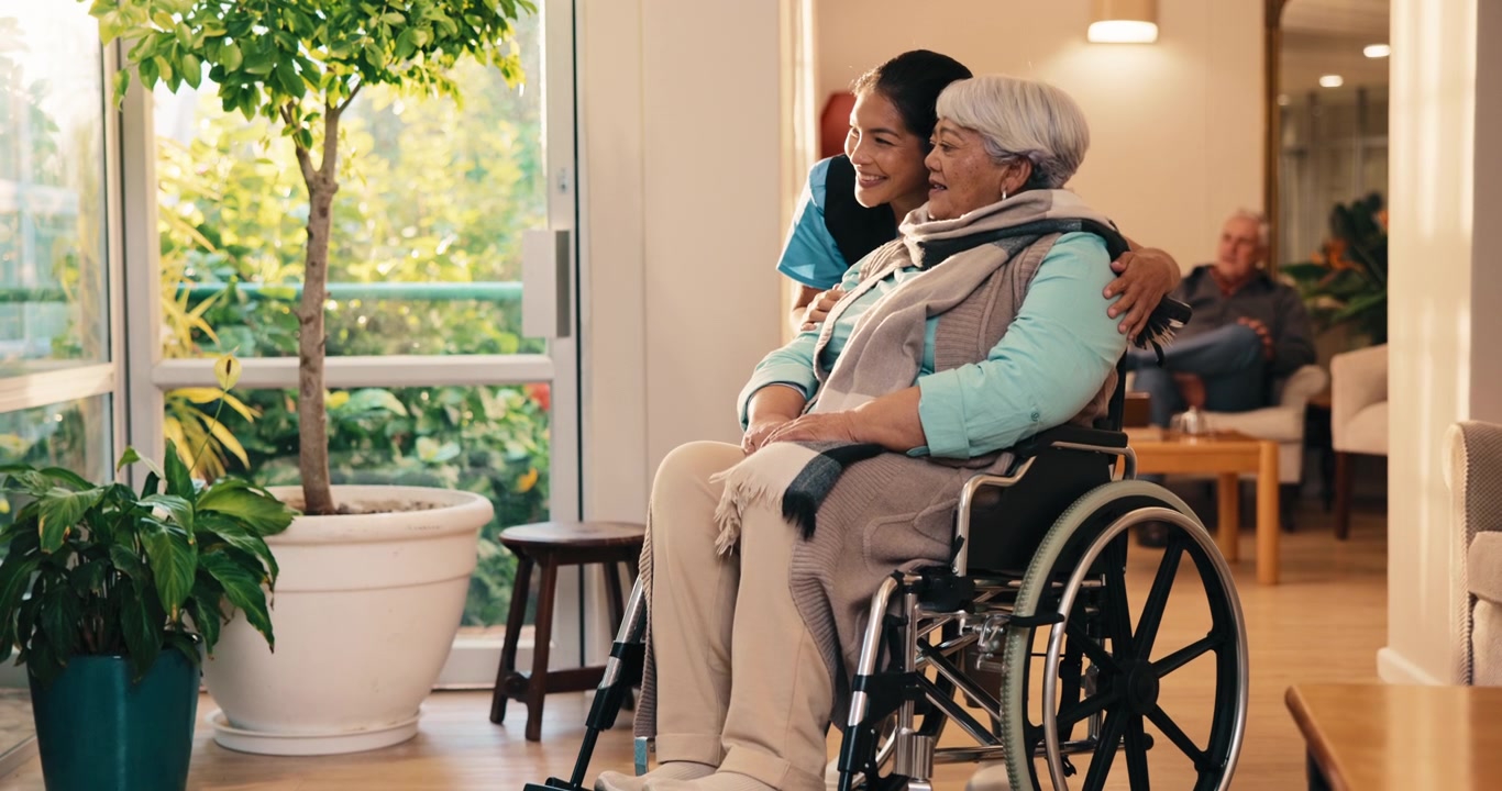 Caregiver and Senior Woman in Wheelchair Looking Out Window