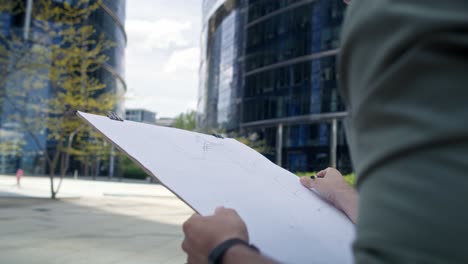 unrecognizable person sketching a building exterior