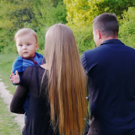 a young healthy father and mother walk with their son in the park