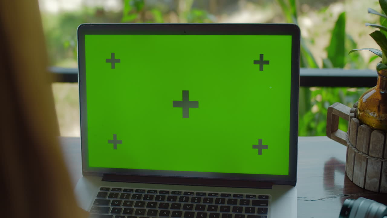 portátil con pantalla verde cerca en la mesa persona escribiendo en el teclado
