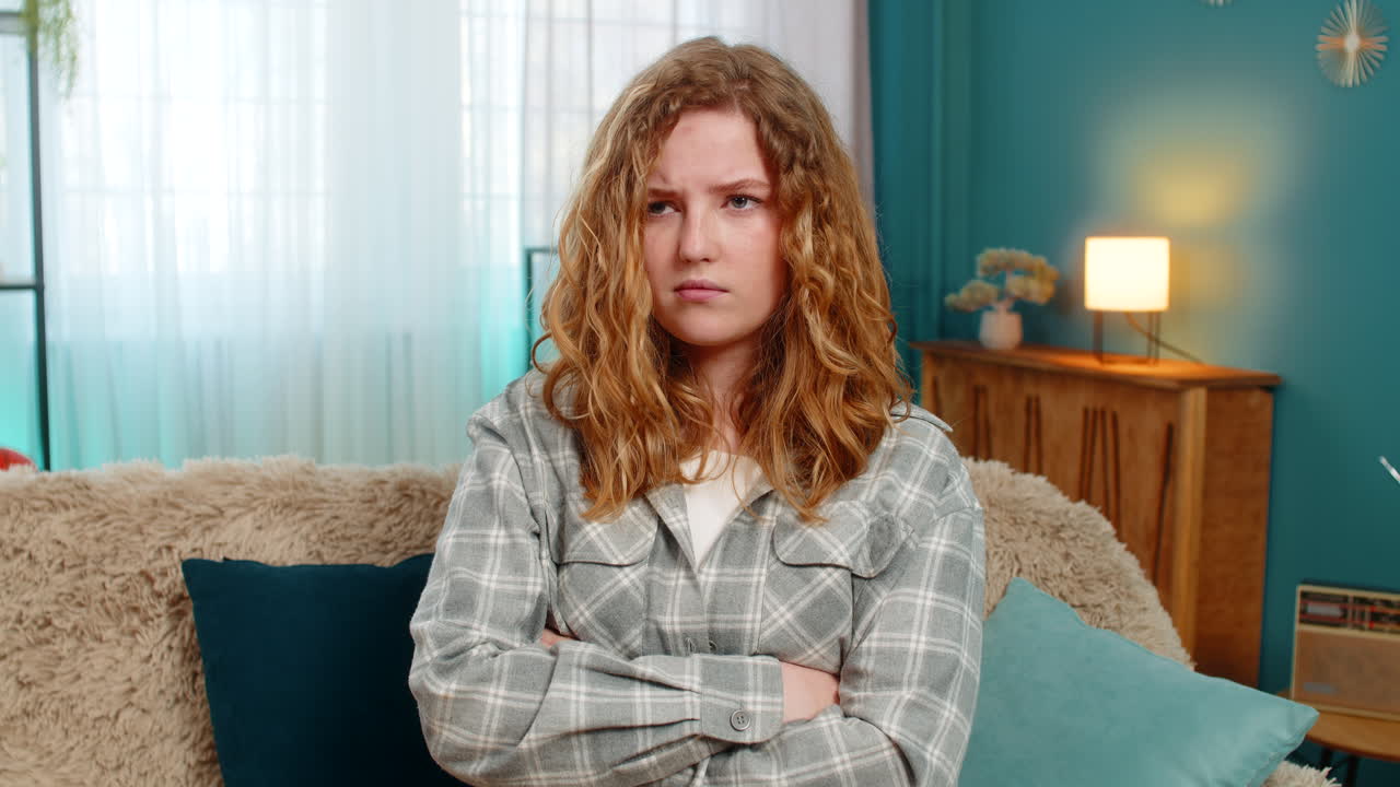 Woman sitting on sofa with crossed arms looking annoyed and displeased showing irritation and anger