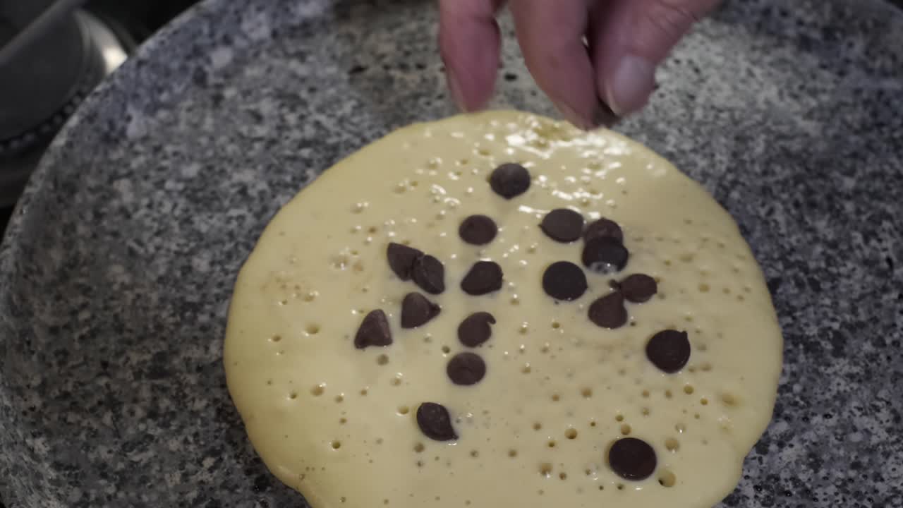hermosa mano coloca chispas de chocolate en panqueques, desayuno de hotcakes