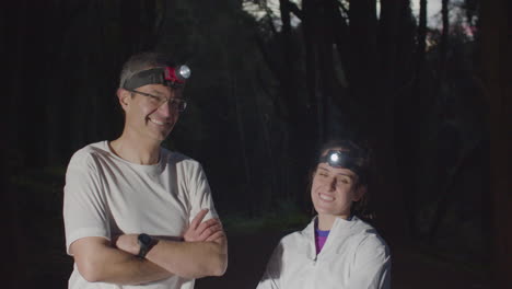 atletas felices con faros en el bosque por la noche