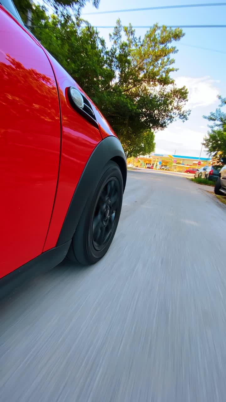 New York, USA, 25 settembre 2025: Vista dal basso di un'auto rossa in movimento su strada. Prospettiva bassa di un'auto rossa che si muove lungo una strada con alberi verdi sullo sfondo.