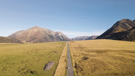lonely car on straight alpine highway in wilderness of south island, nz