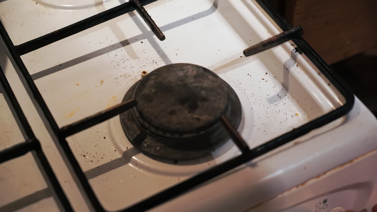 A fire on the stove and a pan with sausage placed on it and shaked