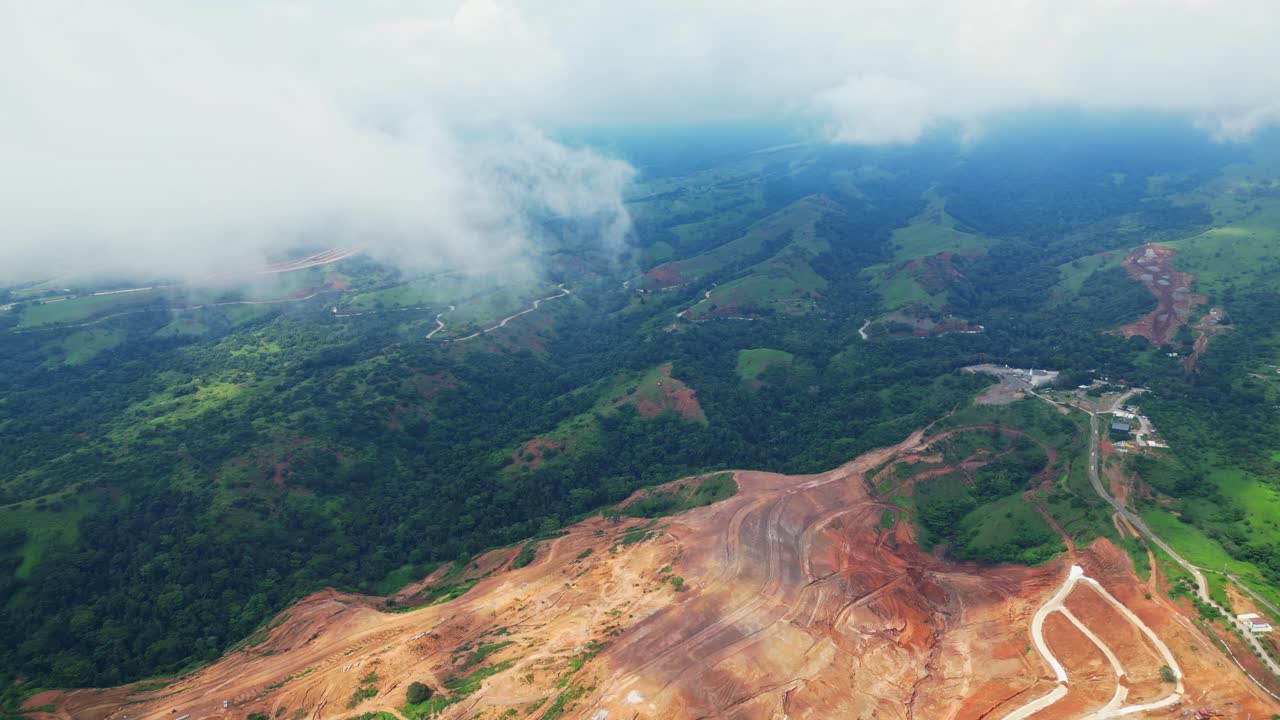 Towering aerial of Tandatangan Signature Golf Course in Mariveles, Bataan, rising above green fairways and winding roads with soft clouds drifting across the scene