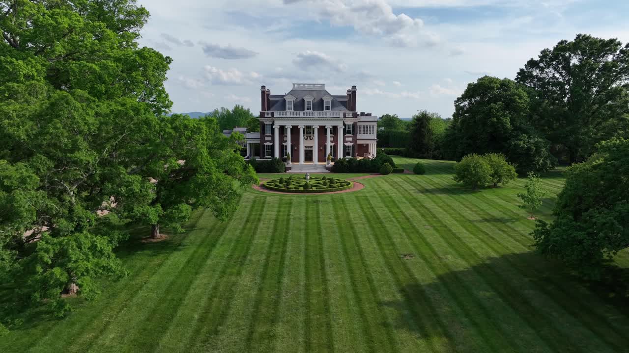 Well-kept garden with grass of luxury mansion building in american town. Sunny day in spring season. Aerial approaching shot. Villa Maria at Rivermont, Lynchburg, VA, United States.