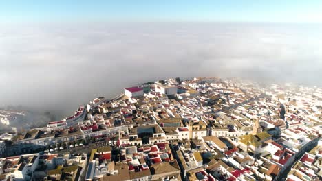 Amplio-Dron-Aéreo-Disparó-Sobre-El-Casco-Histórico-De-Medina-Sidonia-En-Andalucia-España-Con-Edificios-Predominantemente-Blancos-Y-Techos-Rojos-Con-Vistas-A-Las-Nubes-Y-El-Cielo-Azul