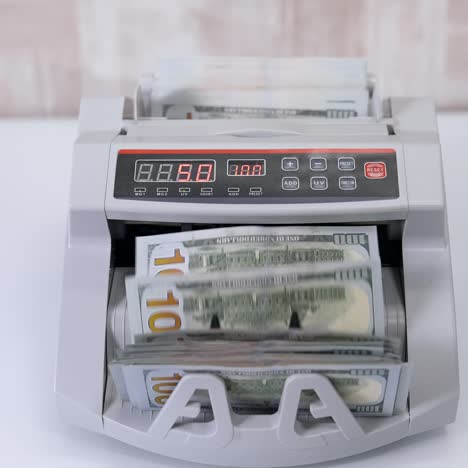 usd on money counting machine. woman putting money into counting machine