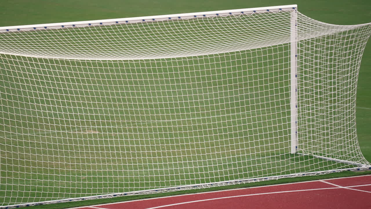 White soccer goal net on green field with running track