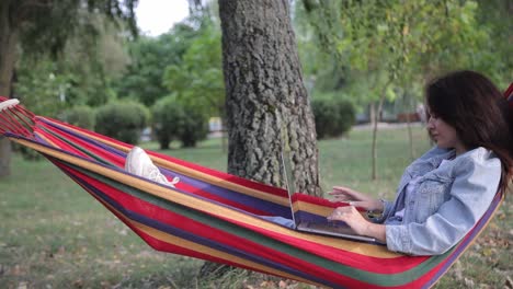 woman working on laptop in a park hammock