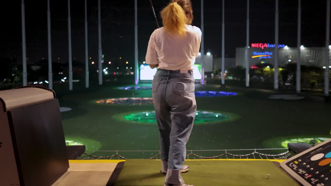 Donna che pratica lo swing da golf al campo pratica