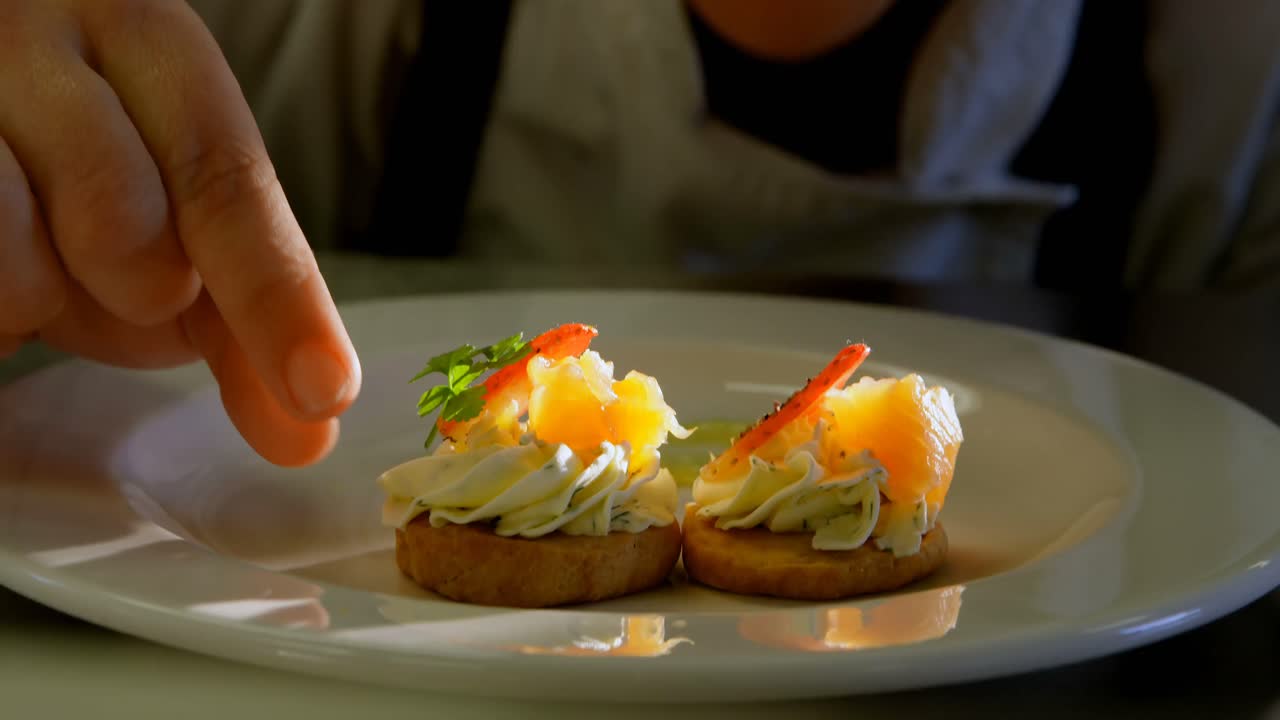 chef femenina adornando la comida en el plato en la cocina 4k