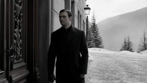 A man in a classic coat by an ornate door in a snowy, mysterious setting