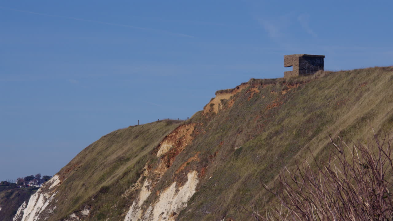 Búnker de hormigón histórico en un acantilado cubierto de hierba con vistas al mar