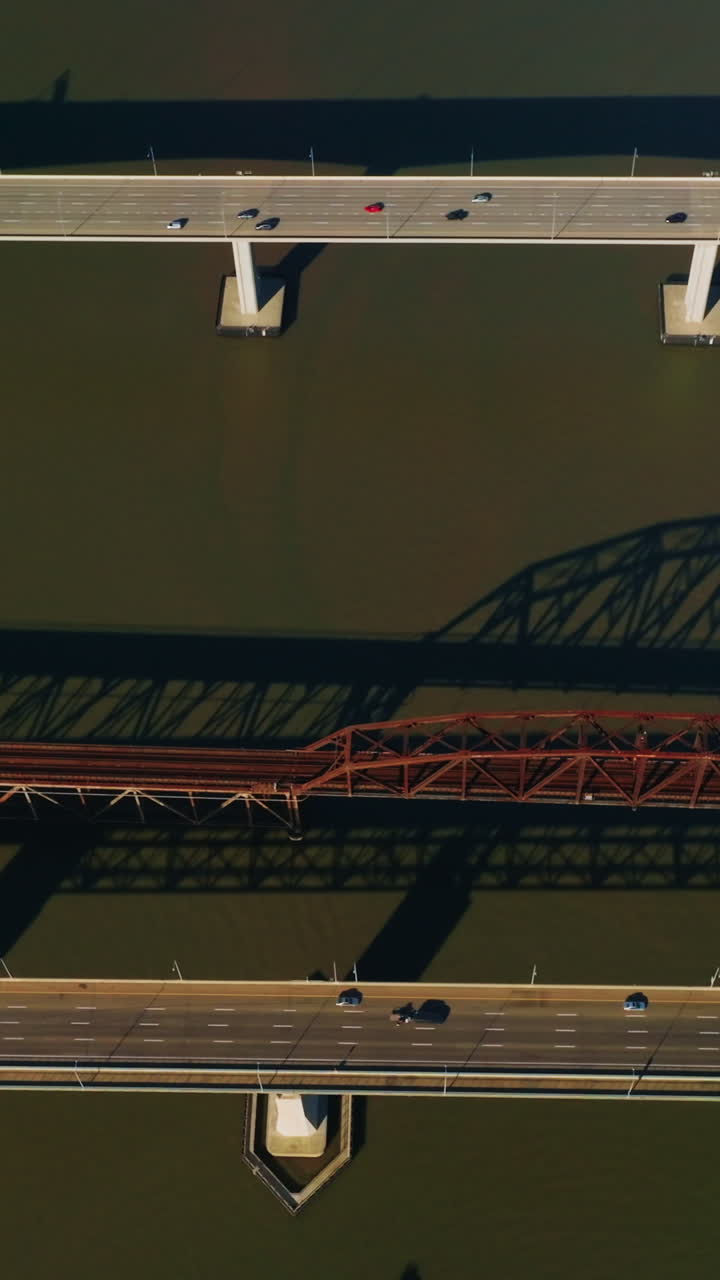 Railway bridge between automobile bridges in Martinez, California, USA. Bird's eye view on the bridges at backdrop of dark water. Vertical video