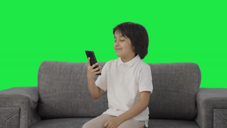 Cute-Indian-boy-scrolling-through-phone-Green-screen