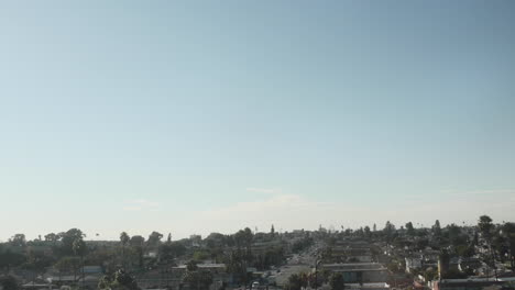 Birds-Fly-Against-Empty-Blue-Sky,-Driving-Shot-Outside,-From-LA-Freeway,-Moving-Car-Shot