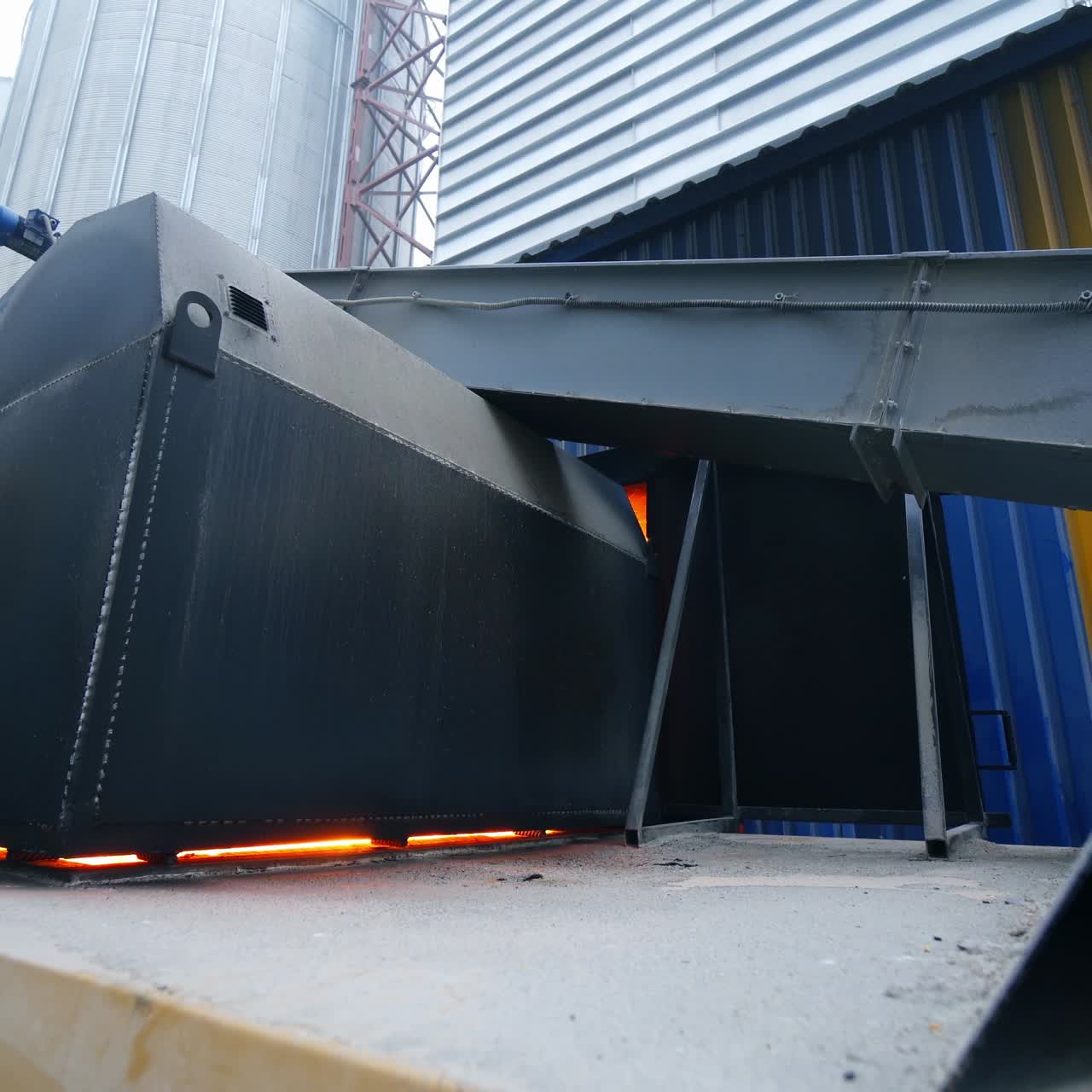 Huge hearth with burning fire inside. Flashes of fire seen in the gaps of the hearth. Furnace place among the granary industrial premises