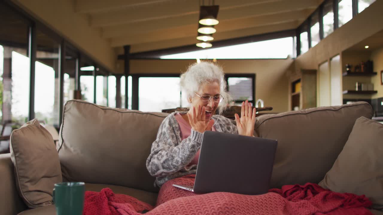 Senior mixed race woman sitting on sofa celebrating
