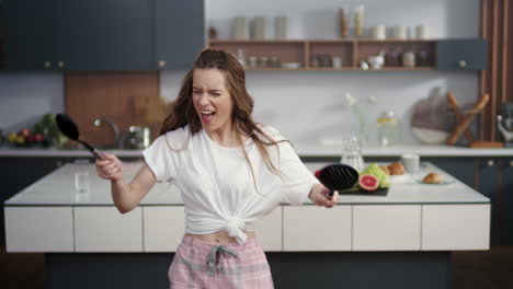 Emotional-woman-playing-on-virtual-drums-with-spoons-on-kitchen-background.