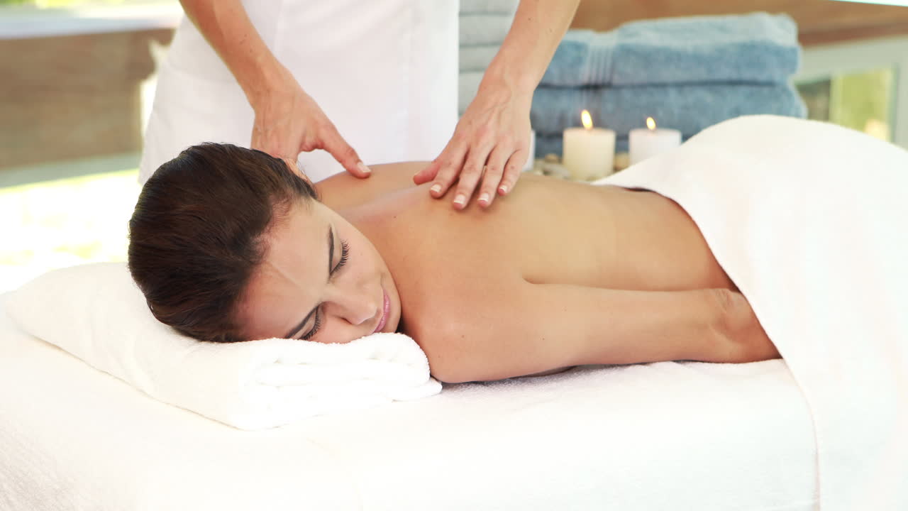 Massør giver massage til afslappende kvinde