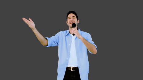 hombre cantando en el micrófono en fondo gris