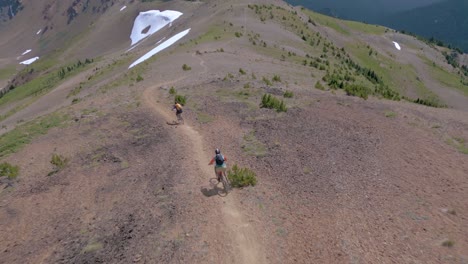 4K-video-of-two-mountain-bikers-riding-fast-on-high-alpine-ridgeline-in-the-remote-wilderness