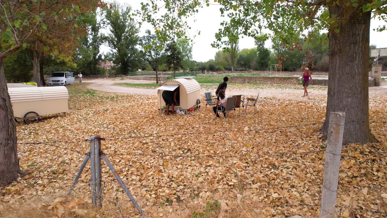 Nomad family resting in countryside near small trailers