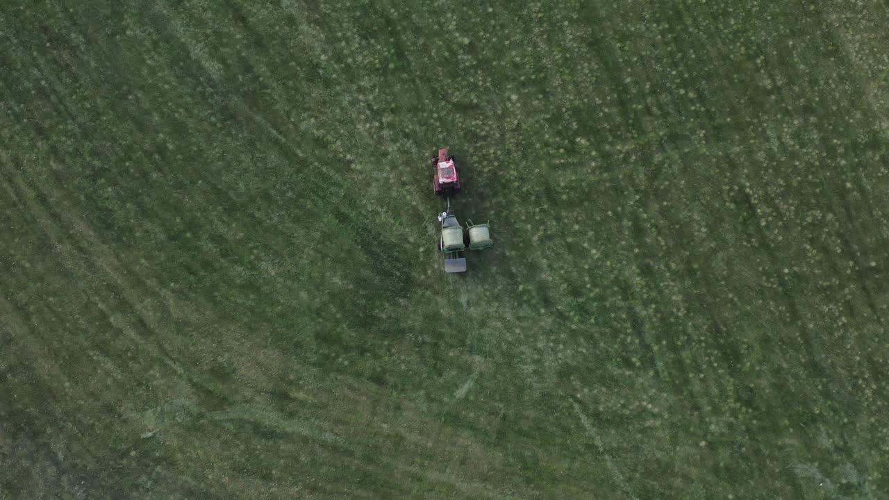 포장 기계가 있는 트랙터가 신선한 녹색 건초 베일, 공중