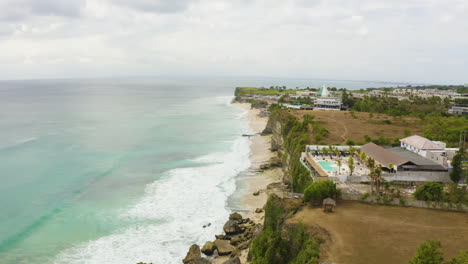 empujando el dron hacia adelante para capturar el resort de la colina en bali indonesia playa de dreamland con vista frontal de la playa al atardecer