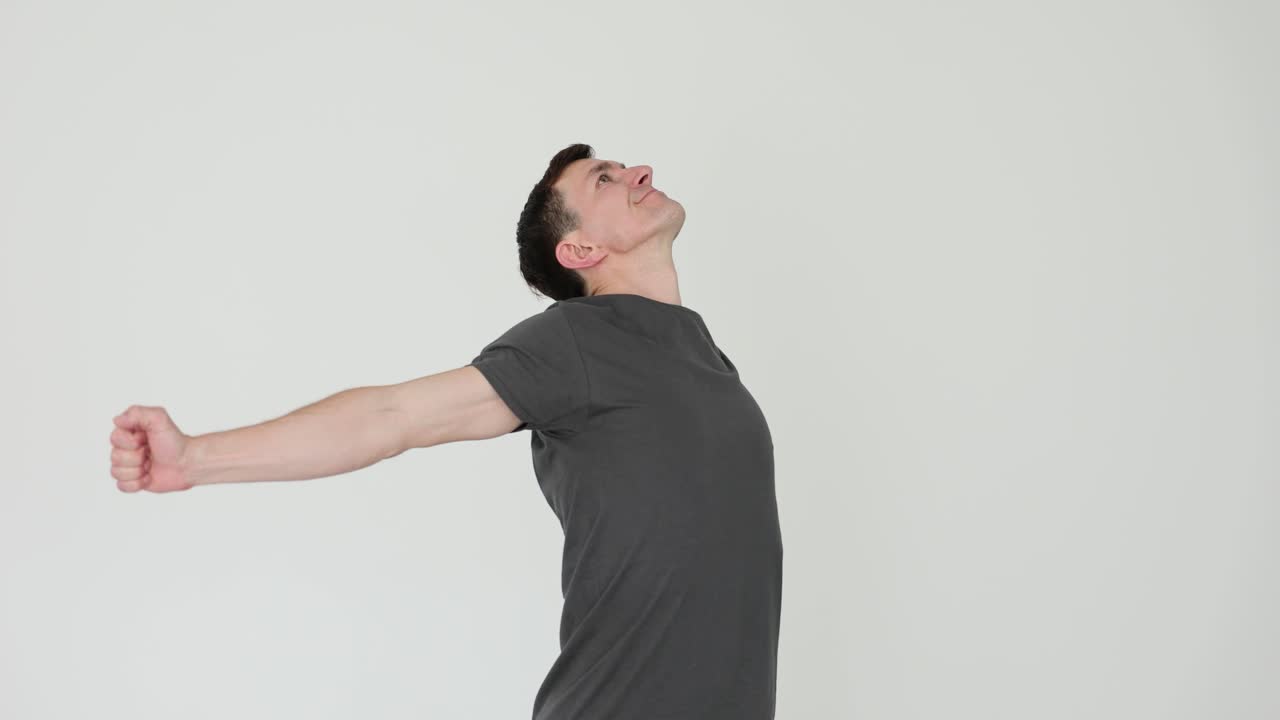 Man with arms outstretched looking up indoors