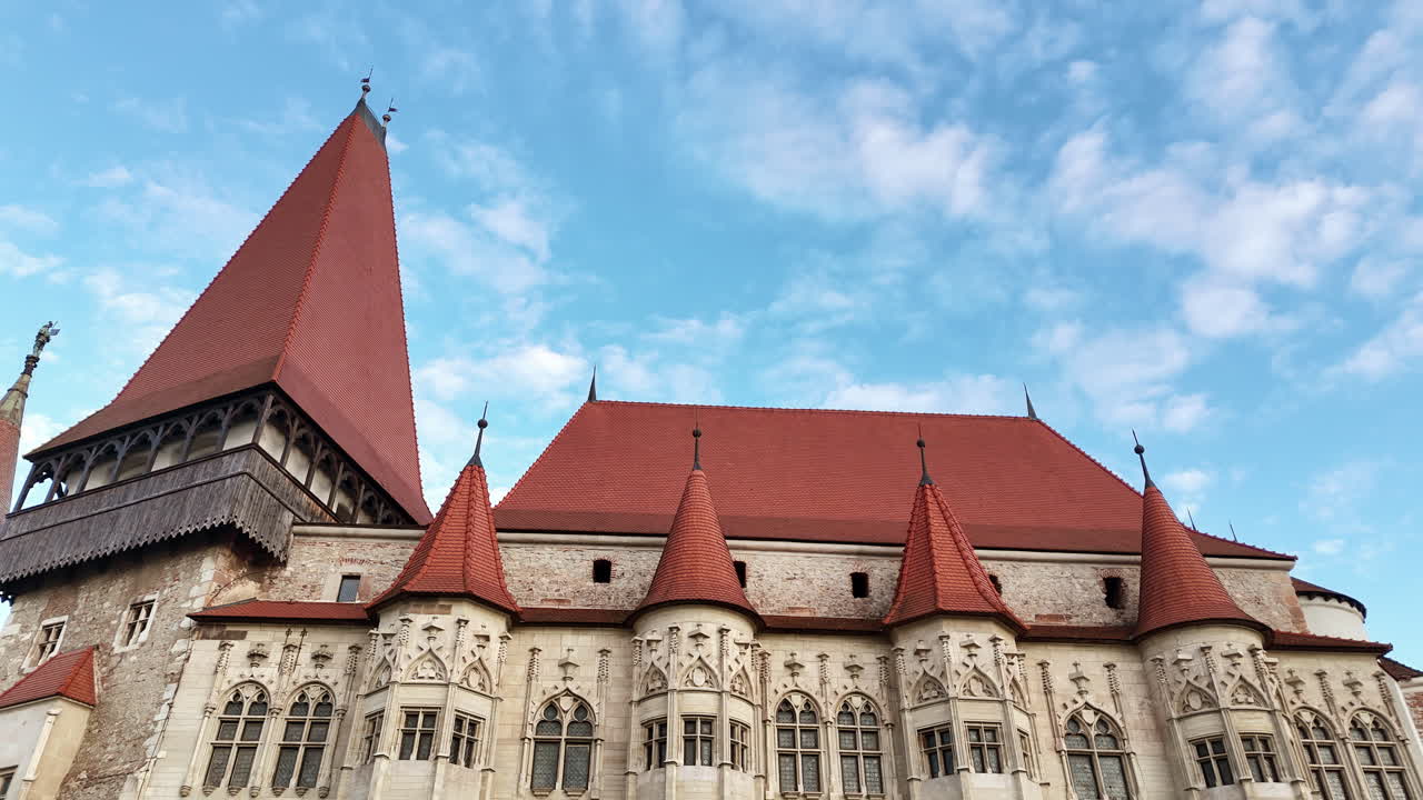Vista aerea con drone del Castello Corvin a Hunedoara, Transilvania. Fortezza gotica medievale con tetti in tegole rosse, torri in pietra e imponenti mura difensive che si ergono sopra la città