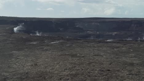 down to up pan of a dark black volcano crater with steam and smoke rising out of the ground