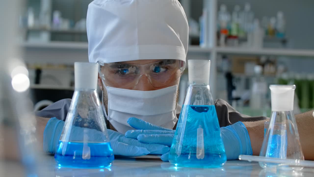 Scientist working in a laboratory with beakers and flasks filled with liquid