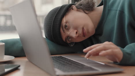 persona cansada durmiendo en una computadora portátil en una cafetería