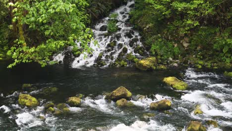 Agua-Que-Fluye-Hacia-Las-Rocas-Cubiertas-De-Musgo-En-El-Río