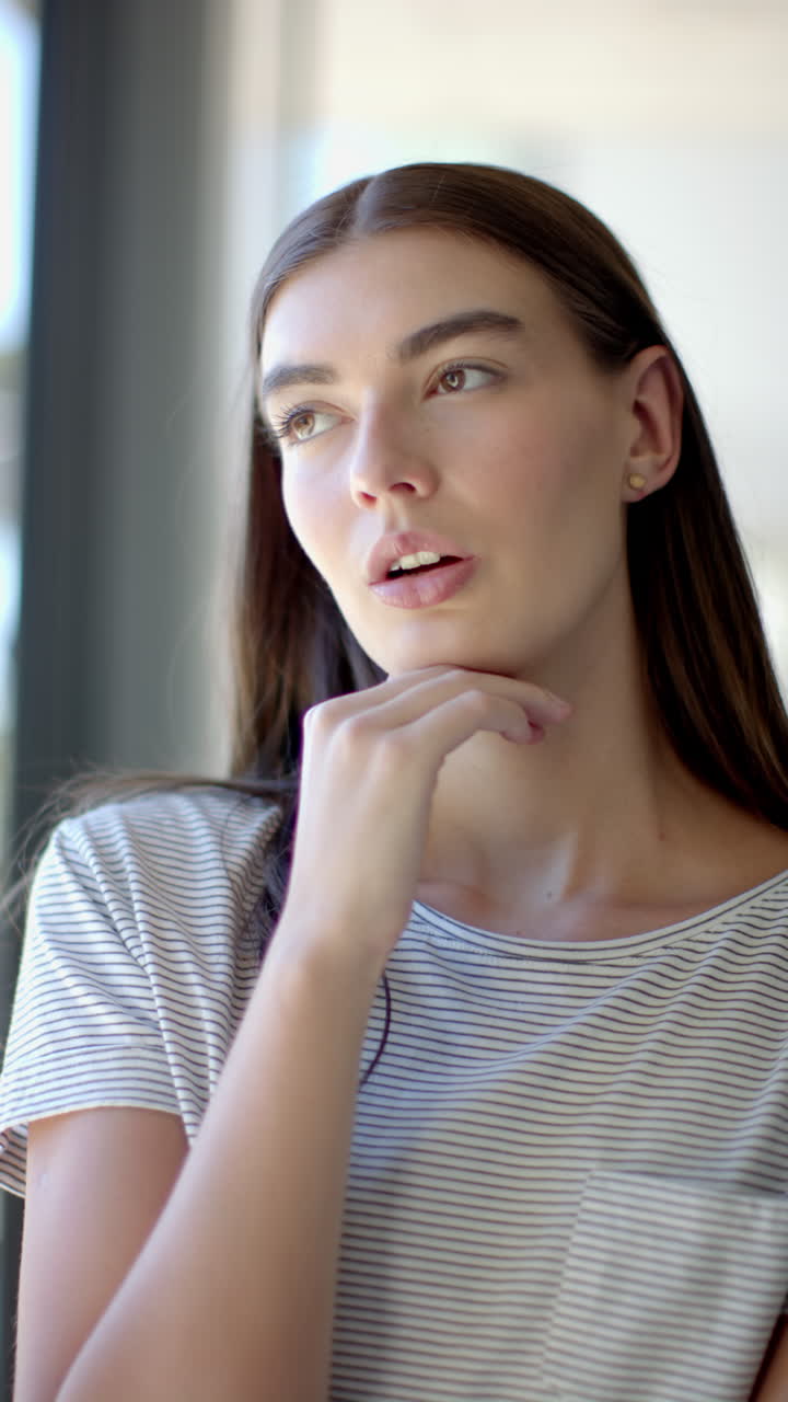 Vertical video: Thinking deeply, teenage girl looking out window at home