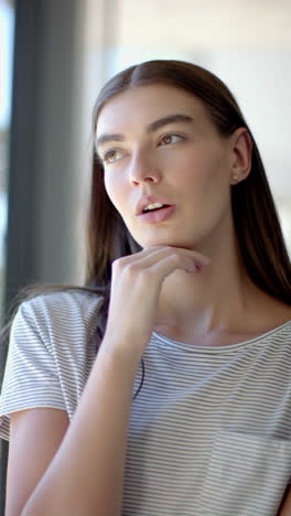 vertical video: thinking deeply, teenage girl looking out window at home