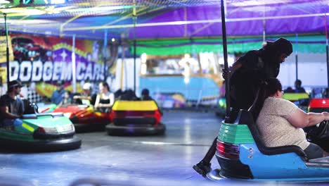 personas disfrutando de coches de parachoques bajo luces coloridas