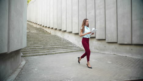 Businesswoman-reading-business-documents-outdoors.-Female-worker-walking-for-job