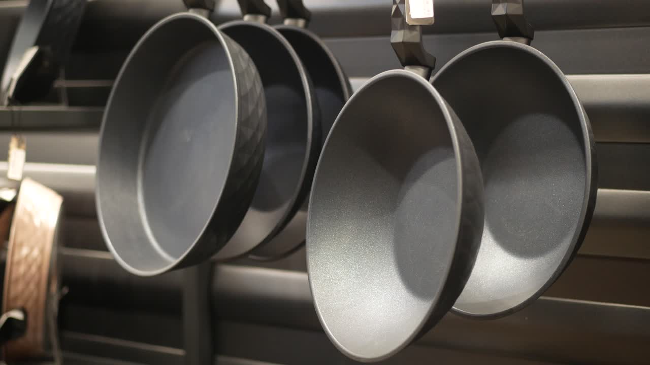 черные сковородки, висящие на выставочной полке