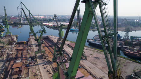 aerial view orbiting large green port cranes in gdansk shipyard, poland