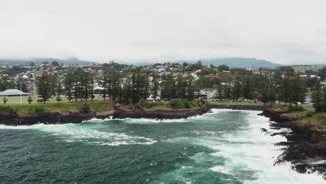 un disparo aéreo de un dron volando hacia la ciudad de kiama en un día tormentoso en la costa sur de nsw, australia