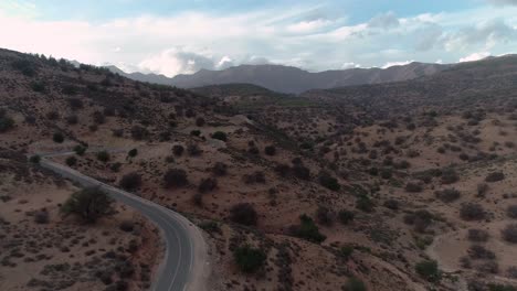 Drone-Aerial-on-Desert-Road-Through-Mountain-Scrub-Bush-4K