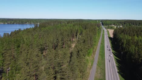 low aerial follows vehicle traffic on northern boreal forest highway