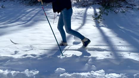 woman walks on the snow with skis and poles on sunny day