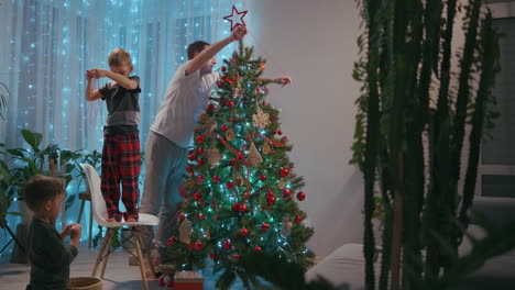 padre e hijo se visten juntos árbol de navidad. decoraciones de navidad para el árbol de navidades la familia decora el árbol de navidad juntos. imágenes de alta calidad 4k